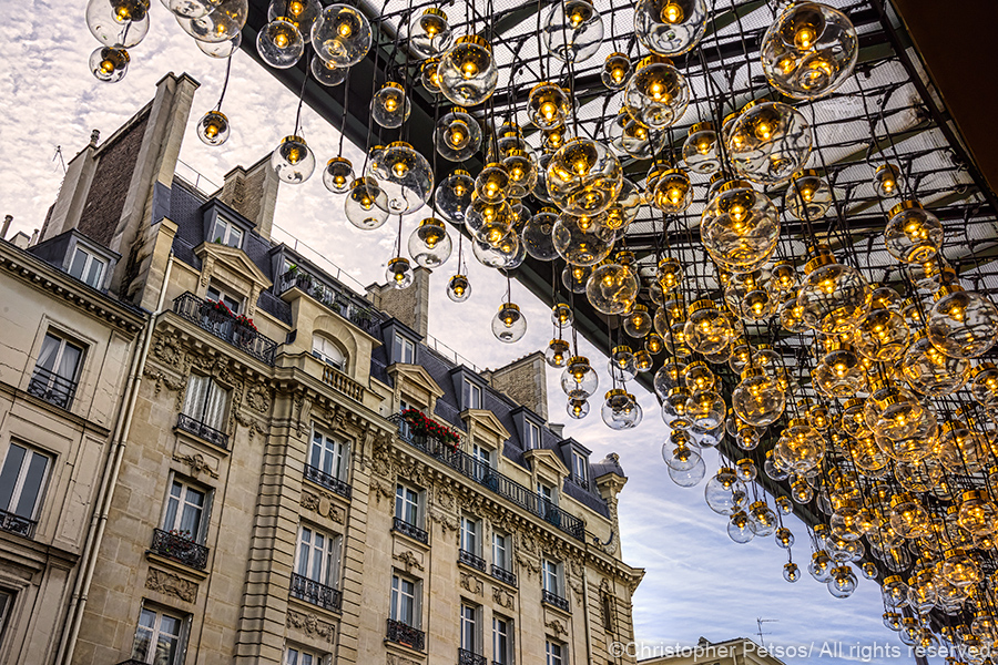 Countless lanterns hanging from an awning at Le Bon Marche with an elgant building in the background