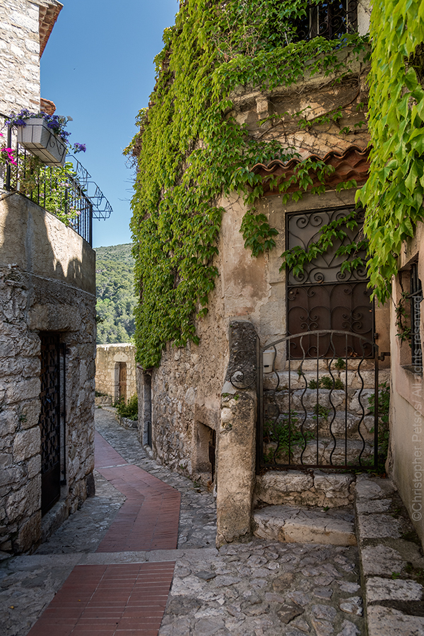 A small street in Eze with stone buildings and ivy