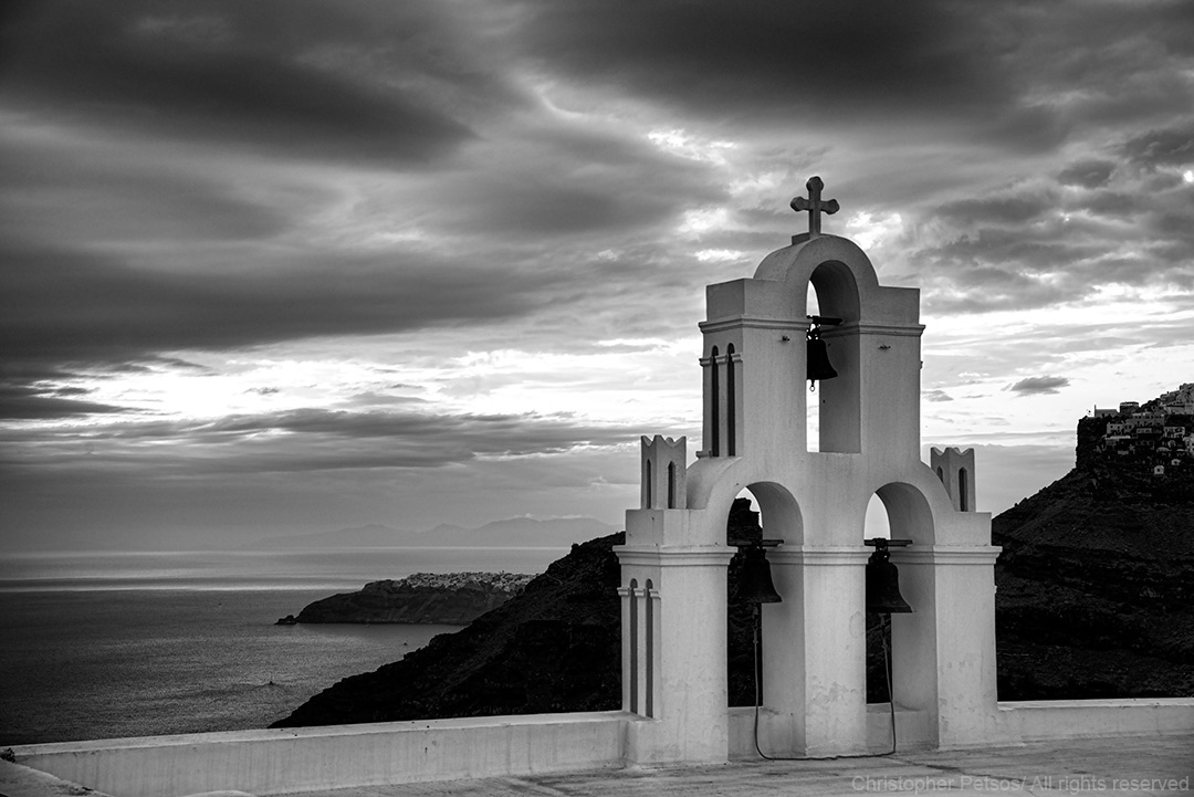 church belfry overlooking cliffs and water with a dramatic sky in black and white