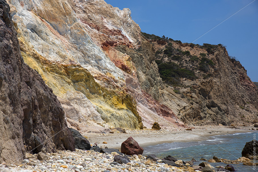 multicolored rock cliffs on a beach at the edge of the water