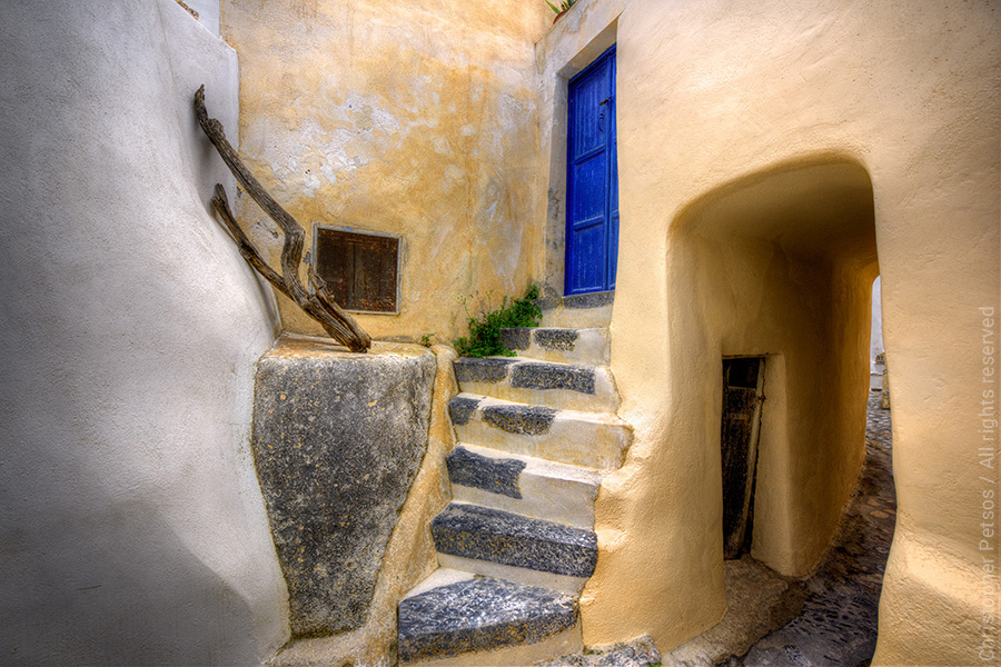 yellow architecture with blue door and arched passageway in Santorini