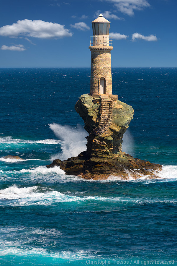 Fine art print by Christopher Petsos of the Tourlitsis Lighthouse off the island of Andros, Greece with waves of turquoise water splashing the rocks