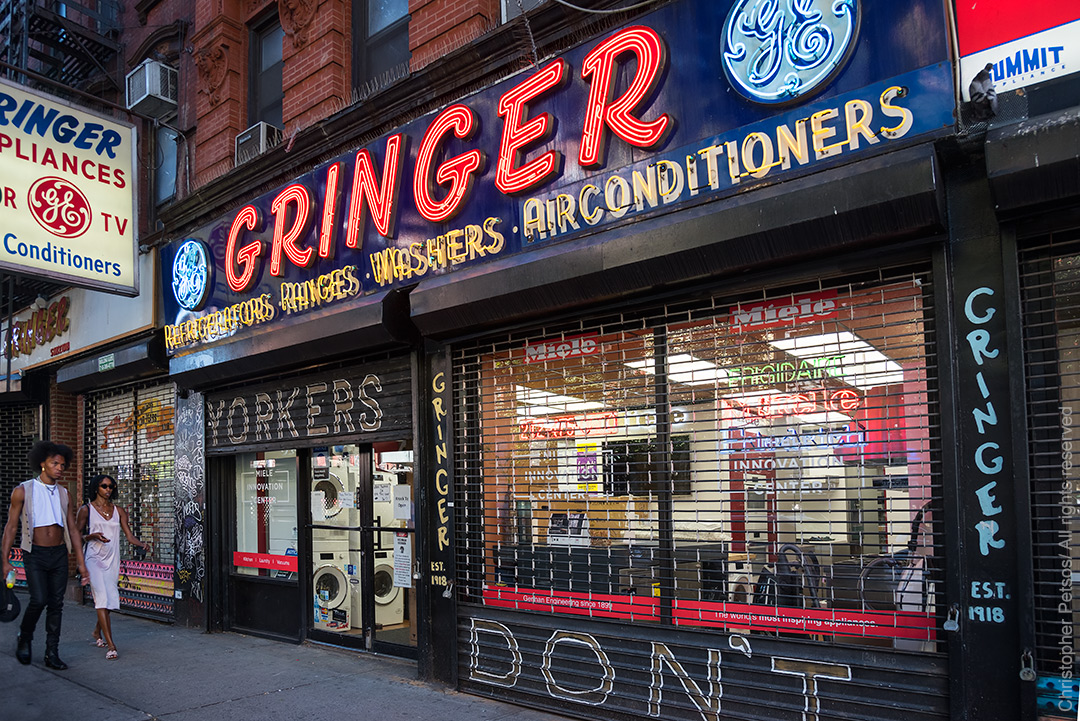 Retro storefront with neon sign saying Gringers and two stylish New Yorkers walking past