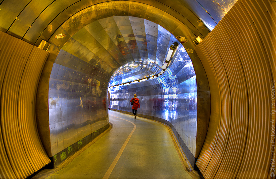 Yellow and silver arched Brunkeberg tunnel with a woman in red walking through
