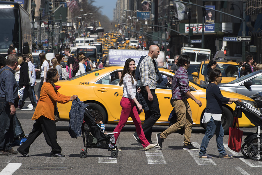 new york city crosswalk with pedestrians and one woman looking at the viewer